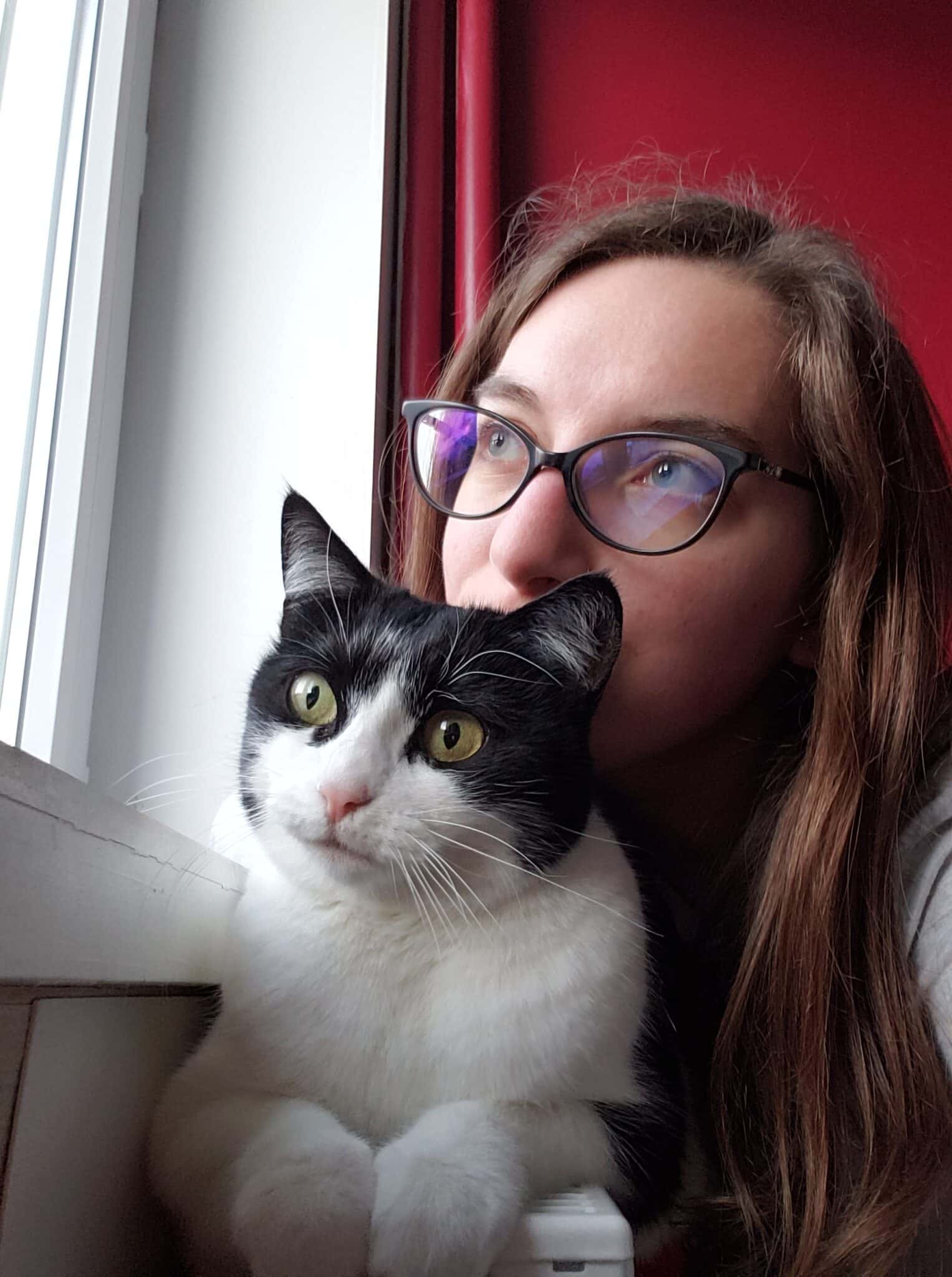 Fille (moi) avec son chat noir et blanc (Nessy) qui regardent au loin à travers une fenêtre.